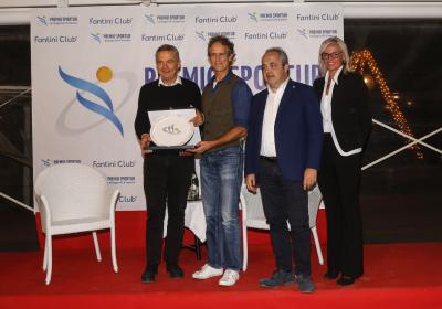 Quattro persone sorridenti su un palco con un premio, atmosfera di celebrazione.