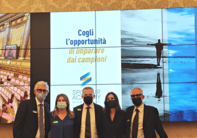 Gruppo sorridente con mascherine, evento ispiratore su imparare dai campioni.