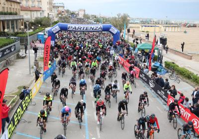 Ciclisti entusiasti partono in massa lungo la costa, pronti per la sfida.